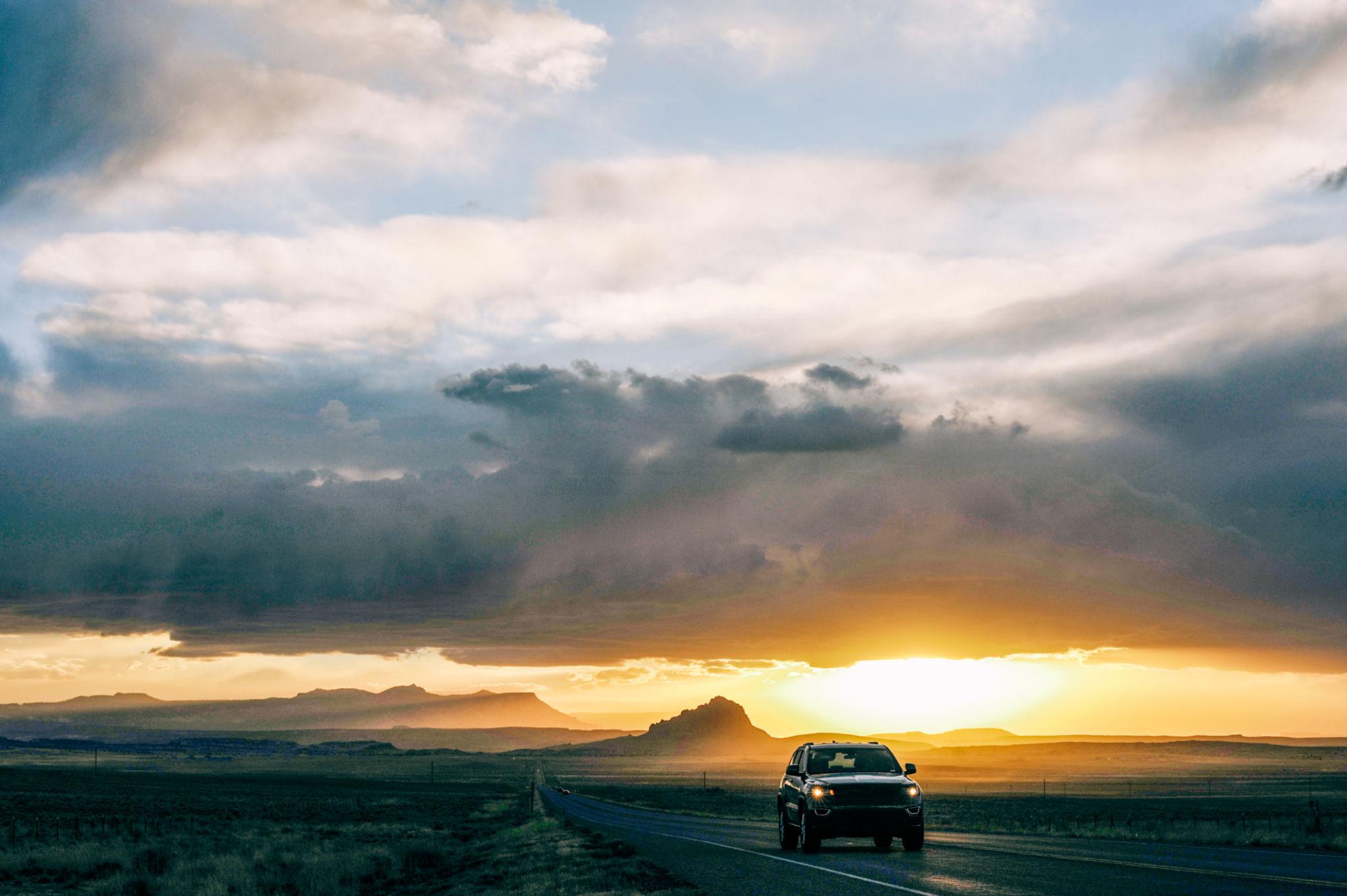 Vehicle on a remote road under dramatic evening clouds